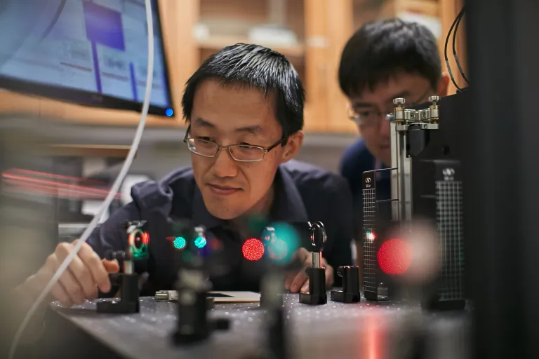 Matt Lew looks over a field of lasers while a student watches